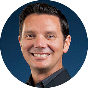 Professor Jeffrey Sanchez Burks A smiling person in a professional headshot against a dark blue background.