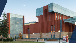 Exterior of the Ross building at dusk with the moon in the sky in the background.