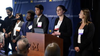 A group of young professionals present at a podium during a business event.