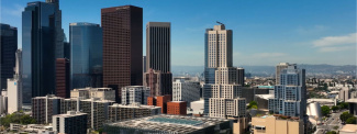 Downtown city skyline with tall office buildings under a clear blue sky.