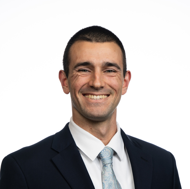 Photo of Joseph Winkler. Man in a suit and tie smiling against a plain white background.