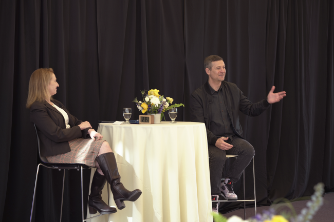 Dean Matusik and Matt Baer seated at a table on stage having a discussion.