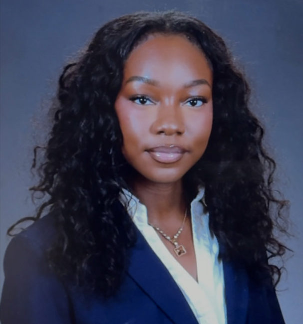 Young woman in a navy suit and white shirt posing for a formal portrait.