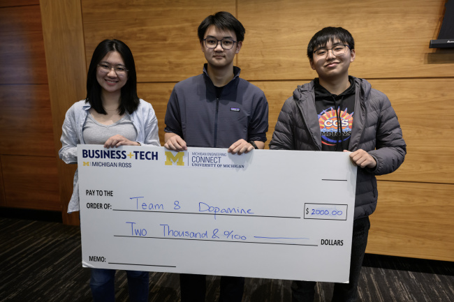 Three people holding a large check for two thousand dollars from the Ross Business+Tech Association.