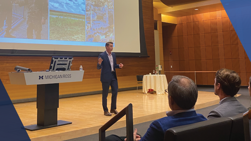 Speaker presenting a slideshow in a lecture hall to a seated audience.