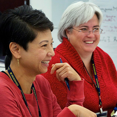 Two women smiling in executive education classroom