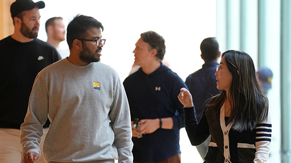 two students walking down a hallway chatting 