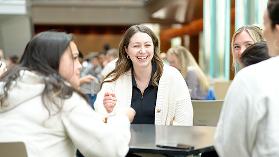 small group of people sitting around a table chatting in a busy room