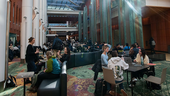 open area full of students sitting on couches and at tables studying 