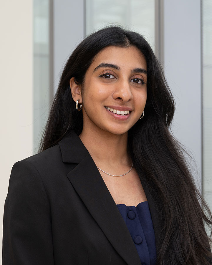 Pavithraa Sudhakar business attire smiling in a professional indoor setting.