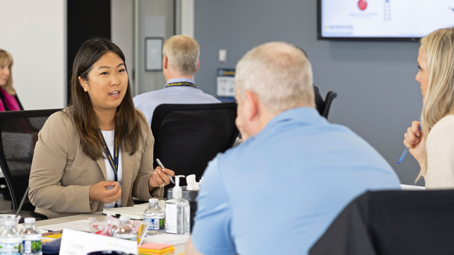 Three people engaged in a discussion around a conference table in a modern office.
