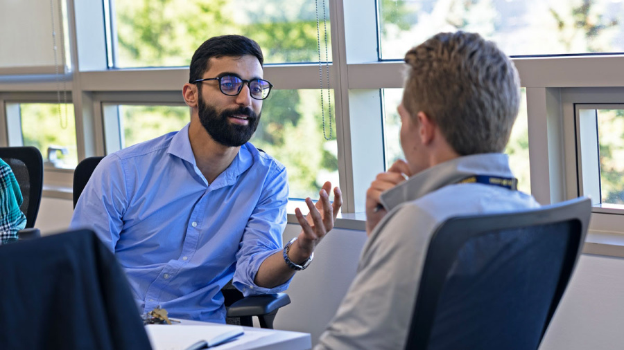 Two people are having a focused discussion in a brightly lit office setting.