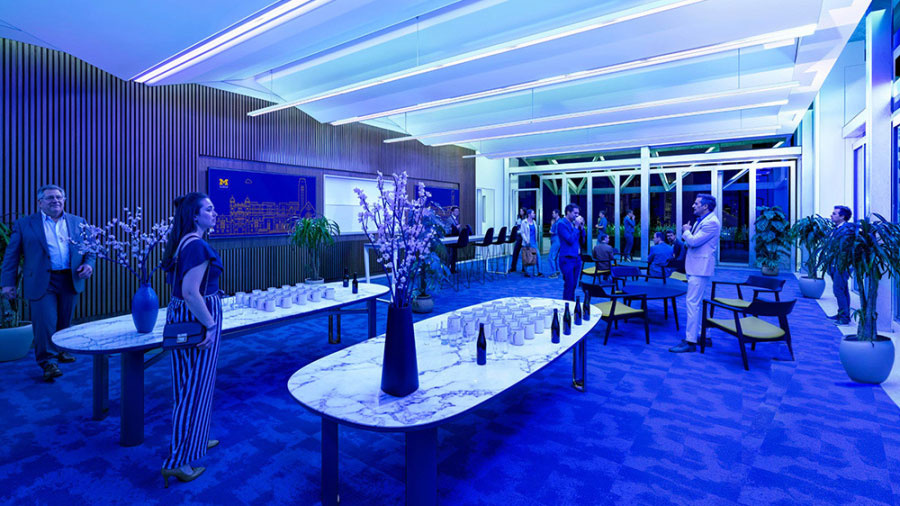 People socializing in a modern, blue-lit lounge set up for a formal event.