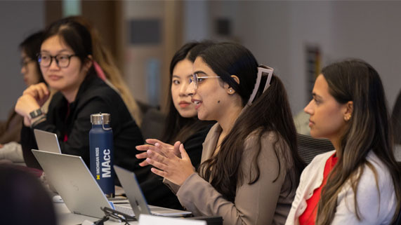 Students engaged in discussion during a classroom setting, with one speaking and gesturing.
