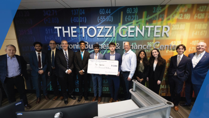 Student winner of the stock pitch competition standing with a large check and the panel of investors at the event