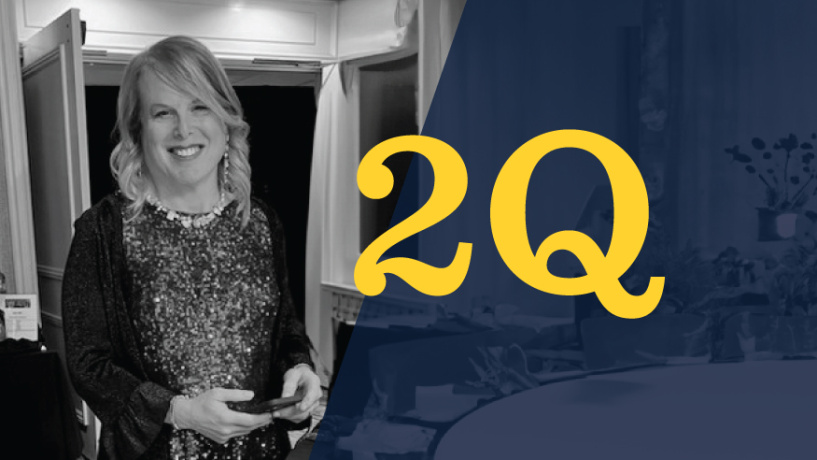A black and white photo of Chrissie in a sparkly dress and cardigan standing in a banquet hall, beside her, the 20Qs logo