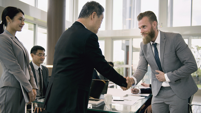 Business partners have introductionary handshake and bow