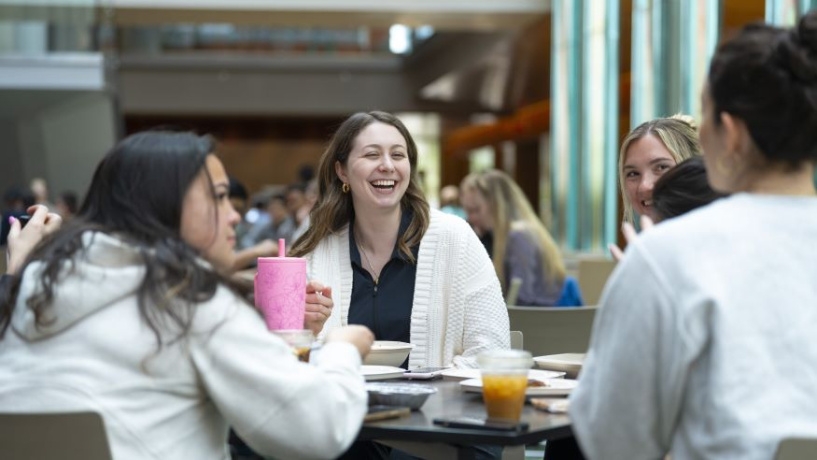 Photo of Michigan Ross Weekend MBA students sitting around a table laughing and talking with each other in the Winter Garden