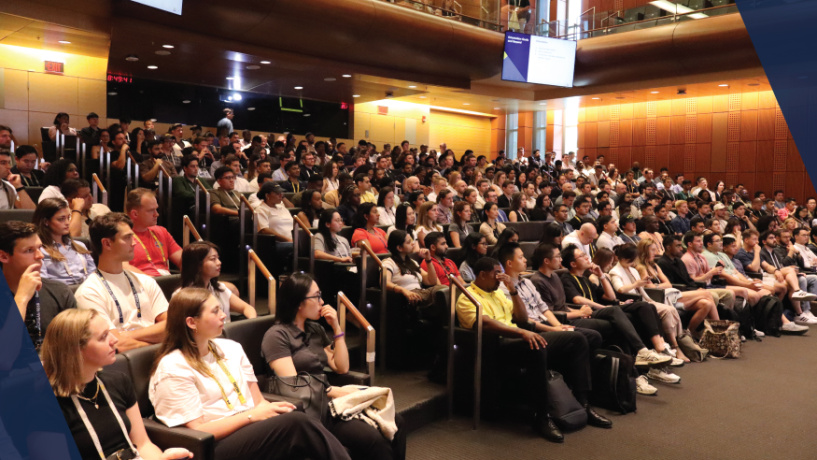 A large crowd of students sits in the auditorium at Orientation.