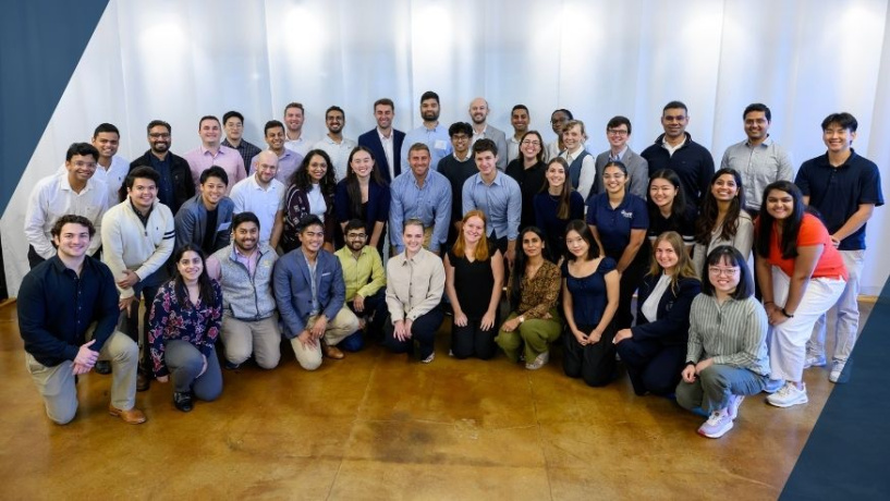 Large group of people posing together and smiling in a well-lit indoor setting.