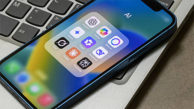 A smartphone resting on a laptop keyboard displays a folder labeled "AI" containing icons for several popular AI assistant apps, including ChatGPT, Gemini, Copilot, Meta AI, Claude, Grok, DeepSeek, Perplexity, and others.