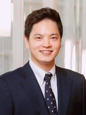 Headshot of a man in a suit, smiling at the camera