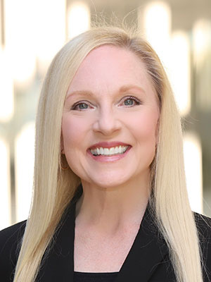 Heather Byrne straight blonde hair wearing a black blazer.