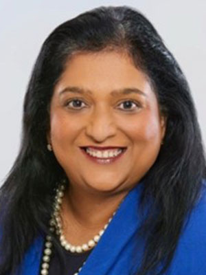 Kanthi Kumar with long dark hair wearing a blue blazer and pearl necklace.