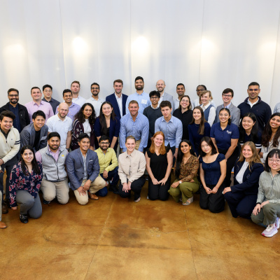A large crowd of people stand in rows for a group photo in a bright room.