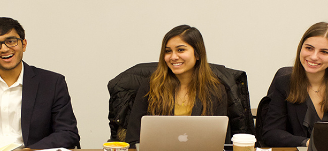 Students interacting at a boardroom table