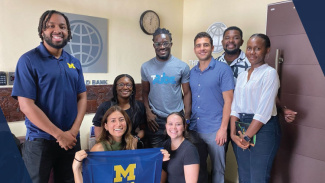 A group photo of students holding a Ross flag at their sponsor company's office.
