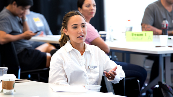 OMBA student talking at a table