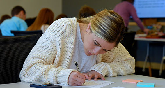 female student writing at desk